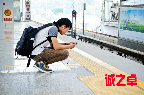 資料圖片：2012年7月18日，在北京地鐵立水橋站，一名年輕人在候車期間查看手機(jī)。新華社發(fā)